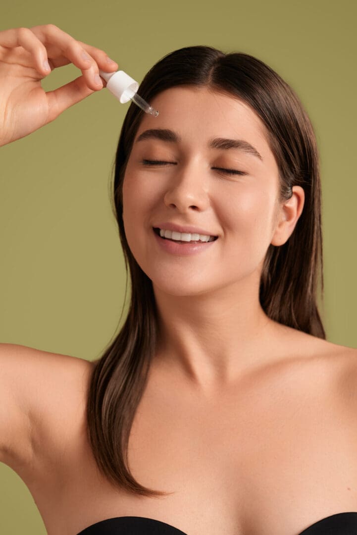 Woman applying skincare serum, smiling contentedly.