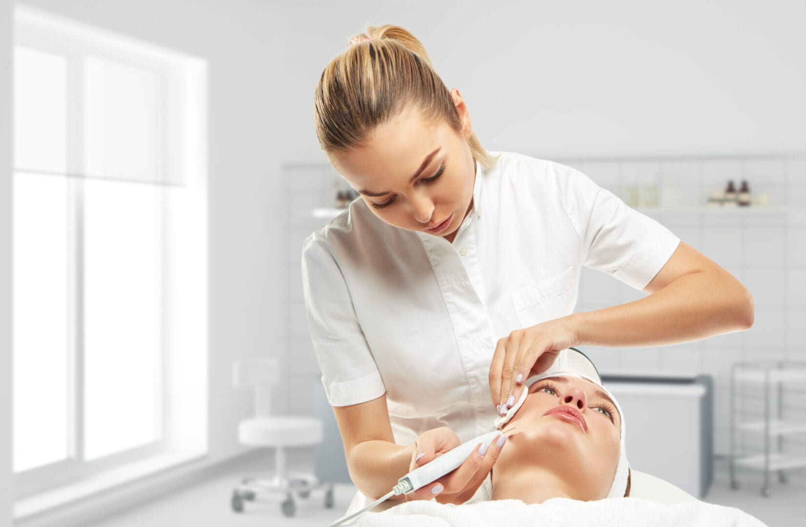 Esthetician performing skincare treatment on client.